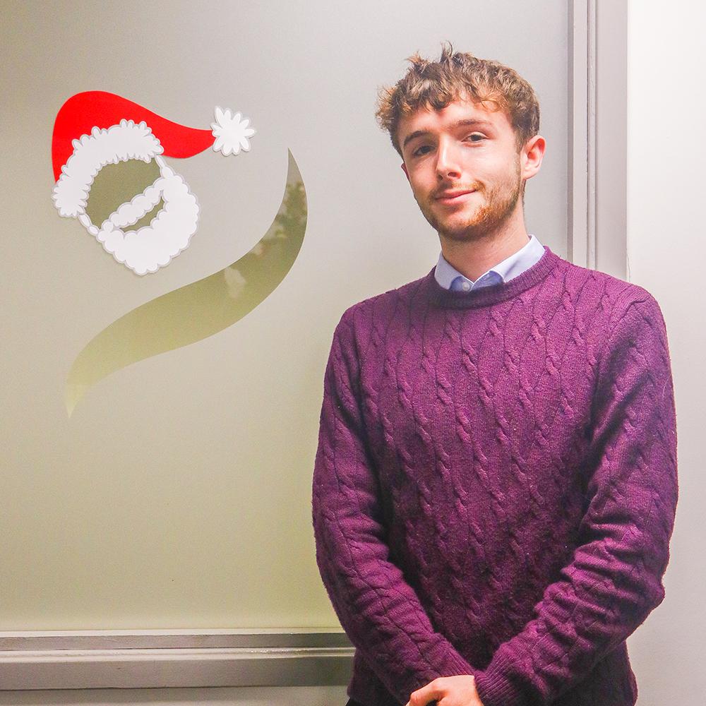 Photo of Digital Mareting Apprentice, Toby, in front of the HBTC logo