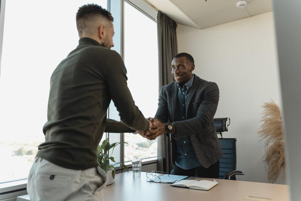 Photo of interviewer shaking hands with interviewee. Apprentice cap has been removed for small businesses