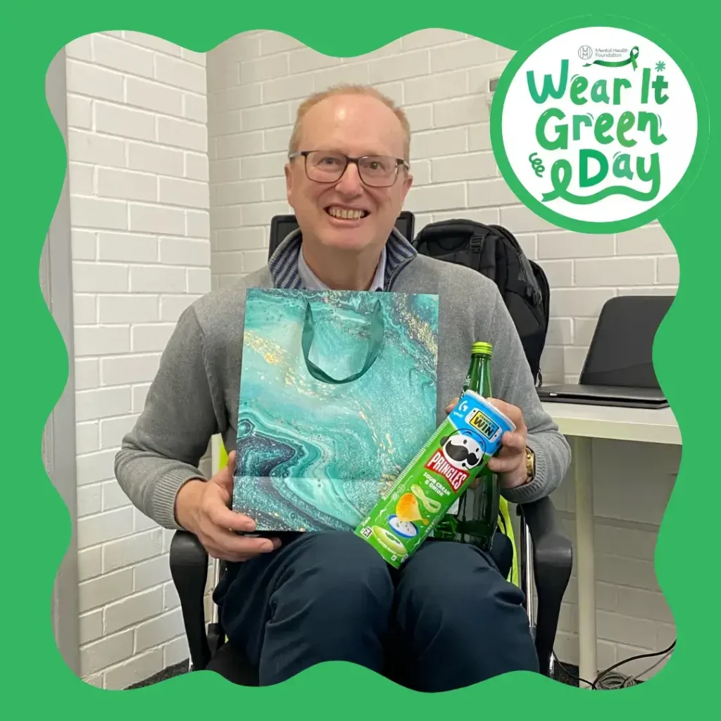 Photo of Richard holding his prize of green-themed goodies from the sweepsteak held for Mental Health Awareness