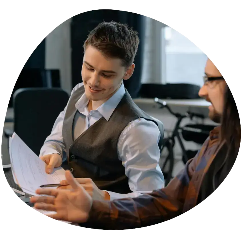 Business apprenticeships : photo of a young male in office attire showing paperwork to a colleague